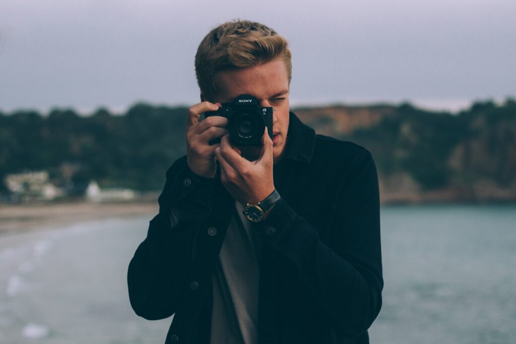 Blonder junger Mann mit Fotoapparat in der Hand