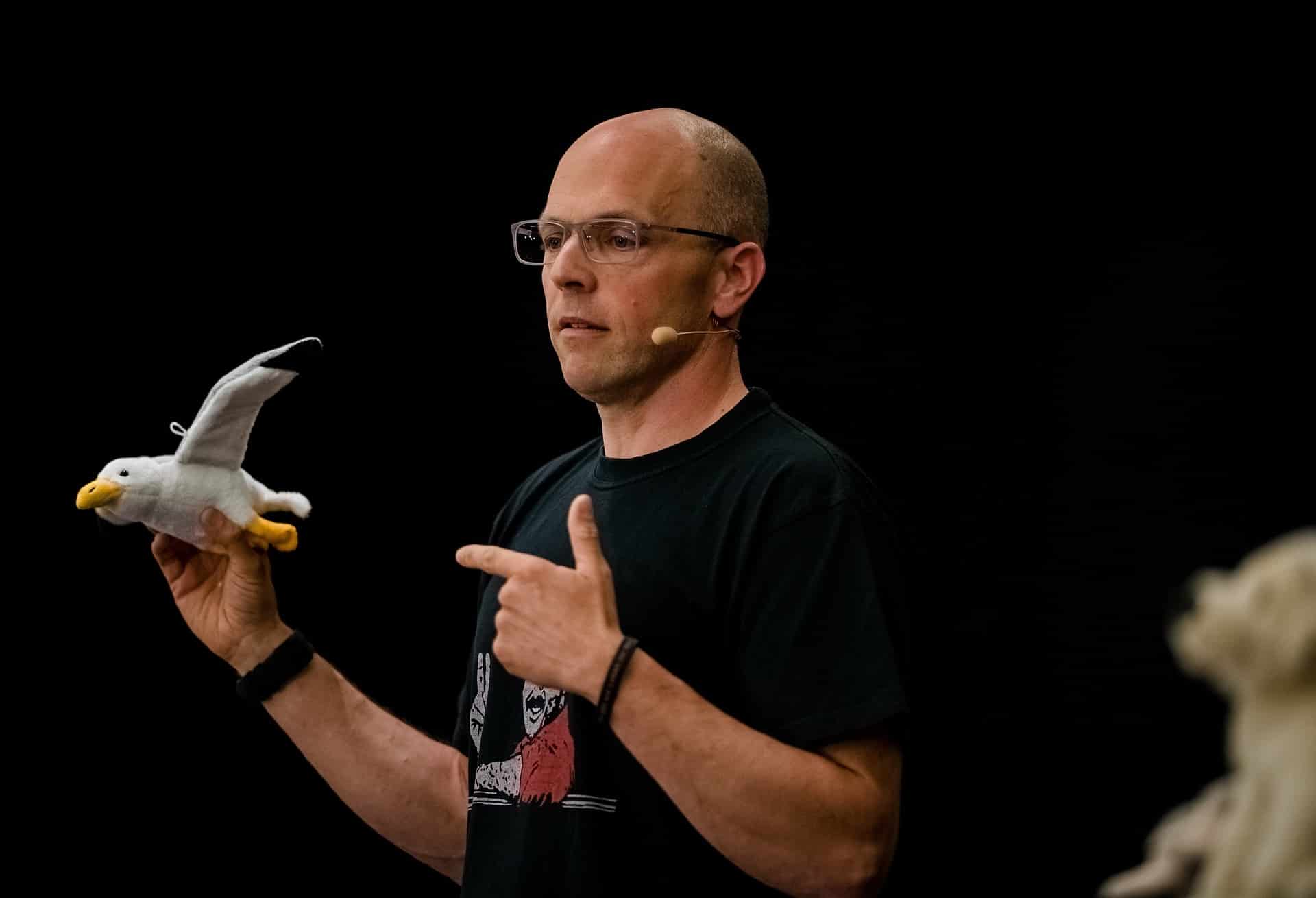 Ein Redner in einem schwarzen T-Shirt mit einer Kuscheltiermöwe in der Hand